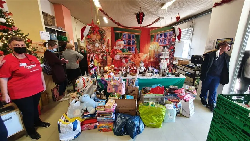 Bénévoles devant un stand de jouets collectés pour les Restos du Cœur, décor de Noël, 1/3
