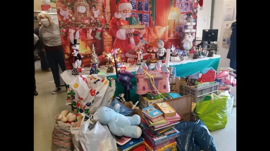 Bénévoles devant un stand de jouets collectés pour les Restos du Cœur, décor de Noël, 2/3